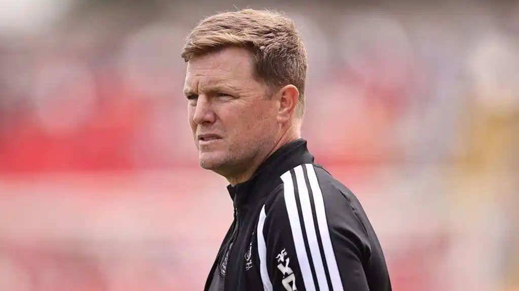 Eddie Howe, wearing a black-and-white tracksuit stop, looks on before a Newcastle match
