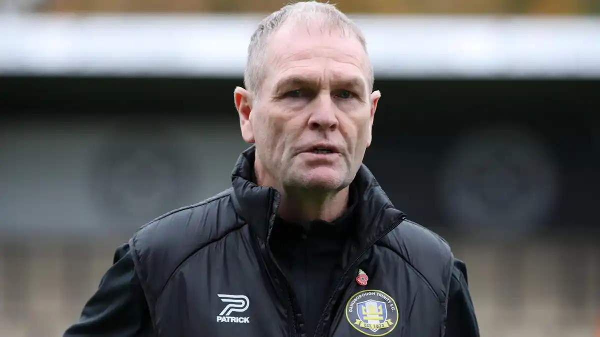Russ Wilcox wearing a black jacket with a Gainsborough Trinity badge on the chest